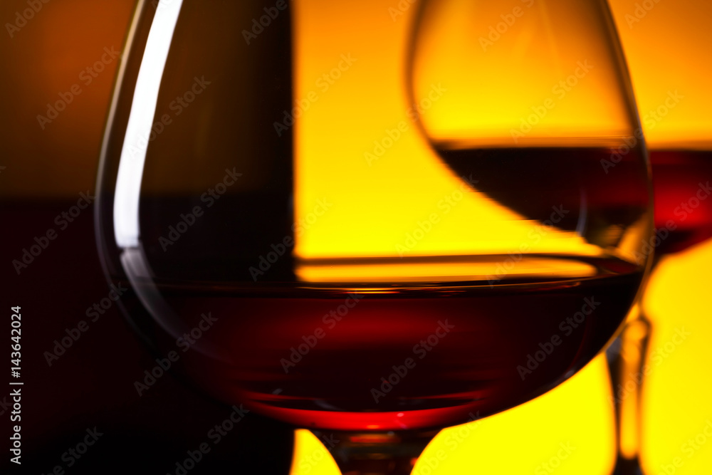  glasses of brandy and bottle on yellow background