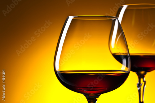 Two glasses of brandy on yellow background