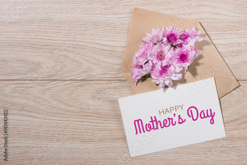 Pink flowers and Mothers Day card on wooden background