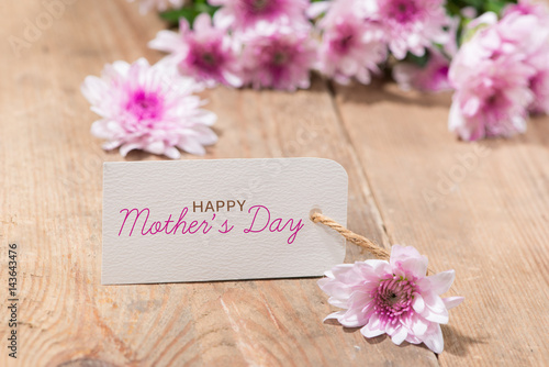 Mothers Day. Tag paper with color flowers on wooden background. Top view. Mock up