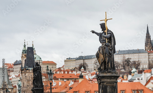 Statue of St. John the Baptist with golden cross on Charles bridge in Prague