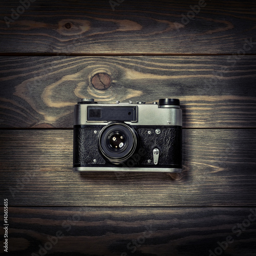 Retro film photo camera on the wooden background.