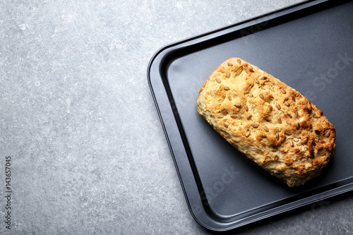 Tasty loaf of beer bread in baking tray on table