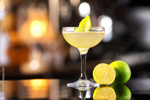 Closeup image of daiquiri cocktail decorated with lemon at bar counter background. photo