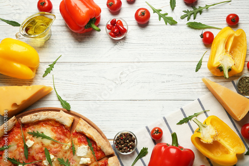 Delicious pizza with ingredients on wooden table