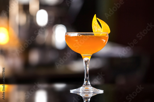 Glass of sidecar orange cocktail decorated with lemon at bar counter background. photo