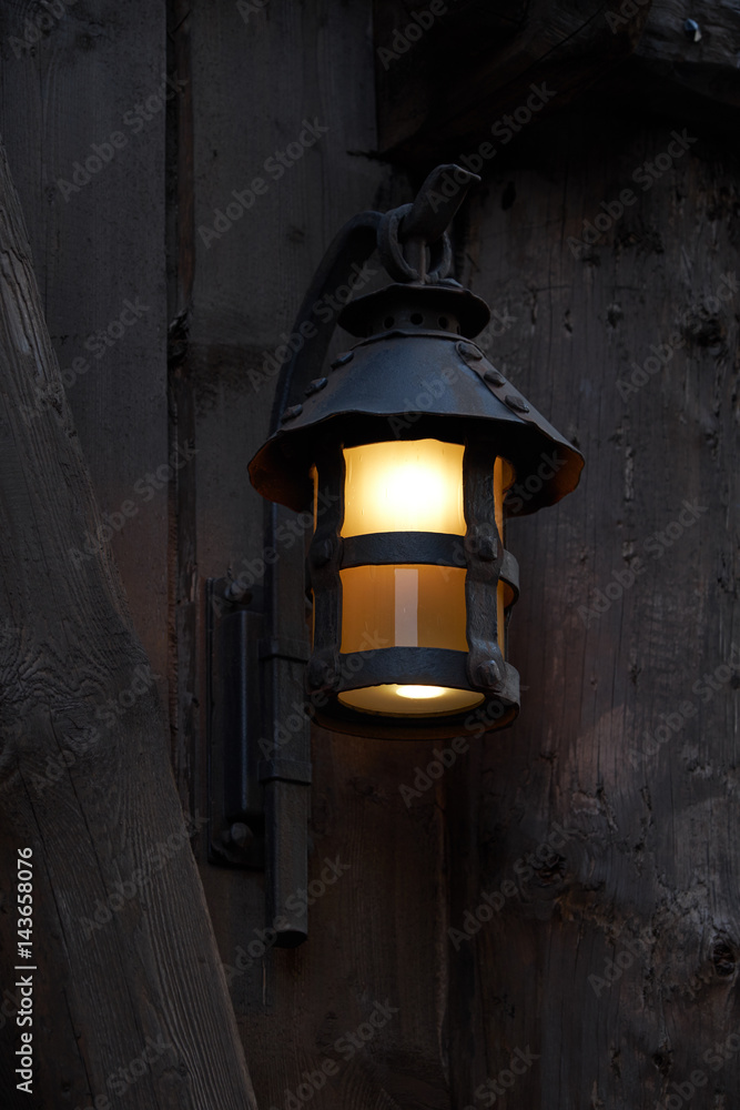 Mystical image of an old lantern at a wooden wall.