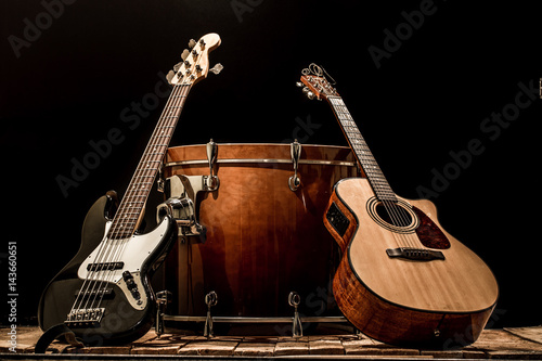 musical instruments, bass drum barrel acoustic guitar and bass guitar on a black background photo