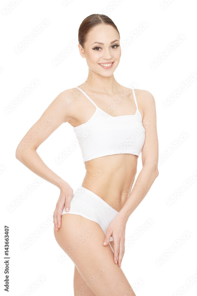 Perfect figure. Gorgeous young happy woman posing at the studio feeling her silky skin touching her upper leg looking to the camera on white background. Perfect figure. Gorgeous young happy woman posing at the studio feeling her silky skin touching her upper leg looking to the camera on white background.