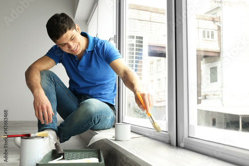 Young man painting window a...