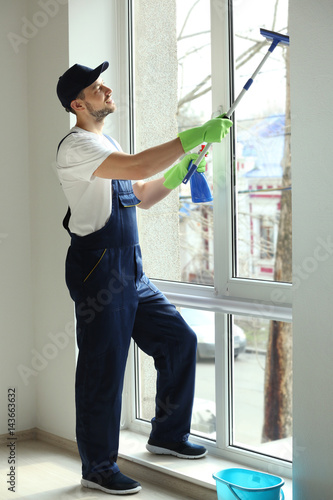 Young man washing window in...