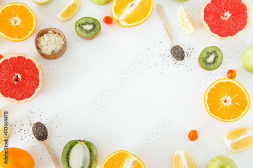 Whole and half citrus fruits and apples lie on a white background.
