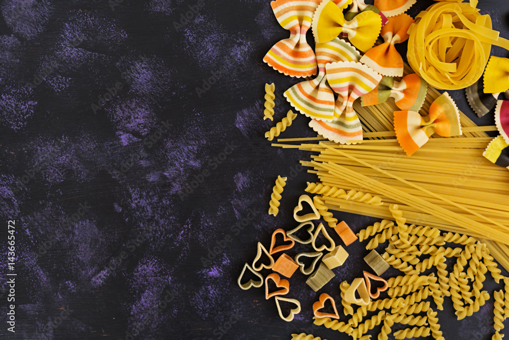 Dry pasta background. Different pasta on dark background. Flat lay. Top view.
