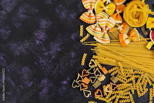 Dry pasta background. Different pasta on dark background. Flat lay. Top view.