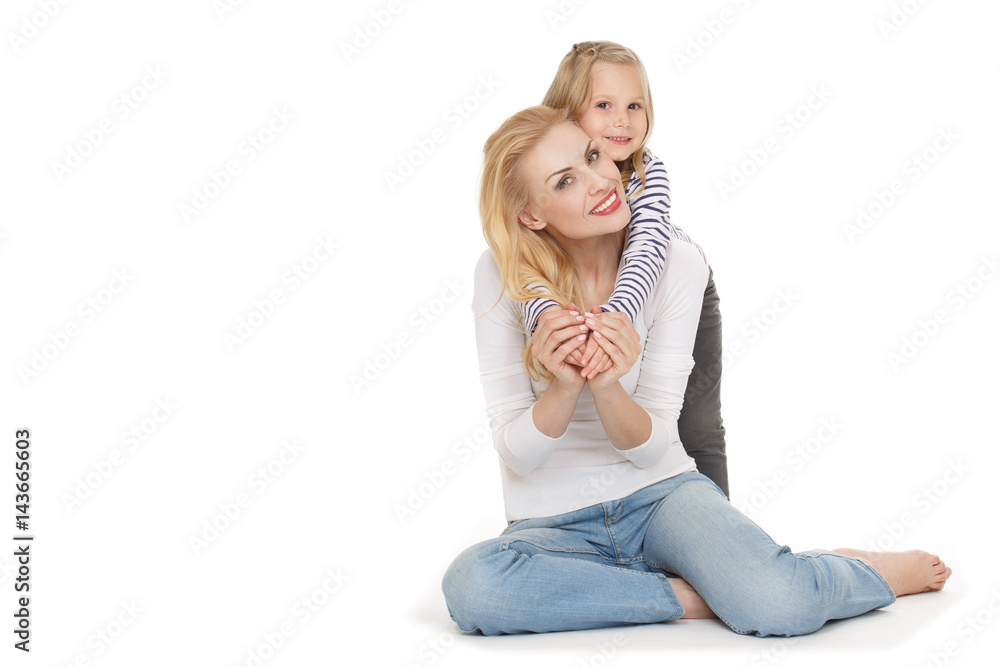True love. Shot of a little cute girl hugging her cheerful mother from behind looking to the camera cheerfully. True love. Shot of a little cute girl hugging her cheerful mother from behind looking to the camera cheerfully.