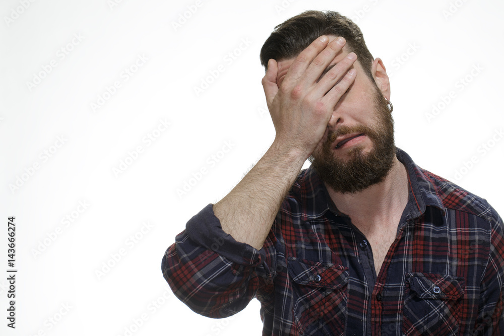 Facepalm. Studio shot of a disappointed bearded man covering his face with his hand on white background. Facepalm. Studio shot of a disappointed bearded man covering his face with his hand on white background.