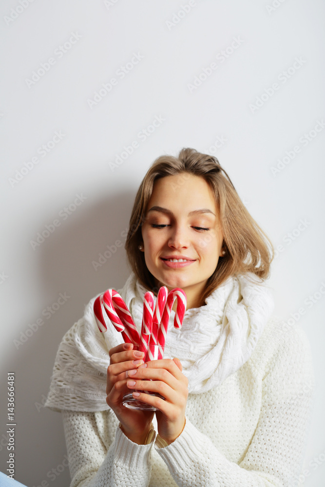 Young woman holding a candy cane, looking at the lollipops Young woman holding a candy cane, looking at the lollipops