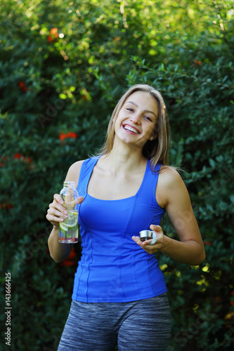Beautiful happy young woman holding bottle of detox water with lemon