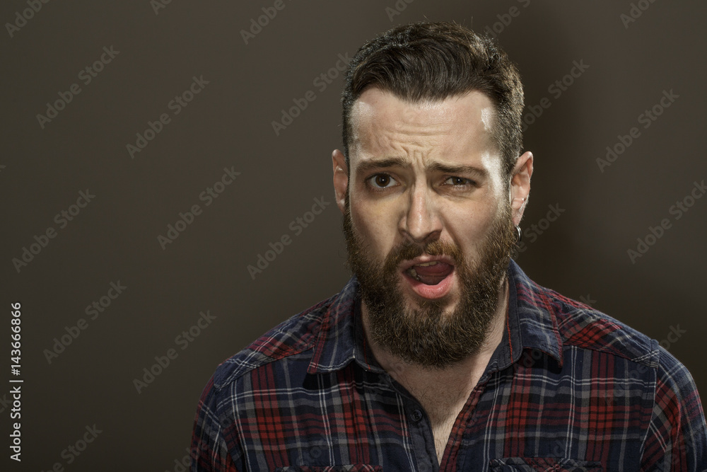 Be smooth. Studio portrait of an attractive bearded male looking to the camera with his mouth open on dark background. Be smooth. Studio portrait of an attractive bearded male looking to the camera with his mouth open on dark background.