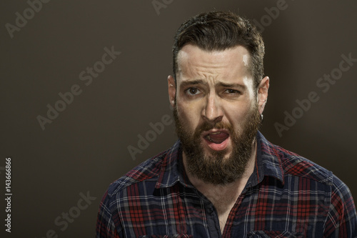 Be smooth. Studio portrait of an attractive bearded male looking to the camera with his mouth open on dark background.