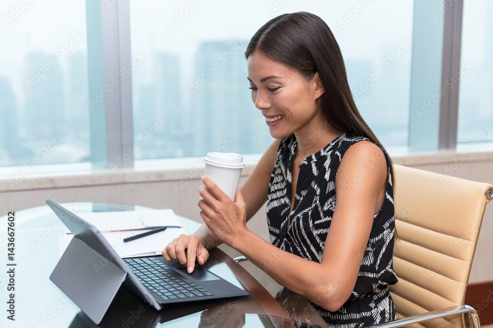 Businesswoman drinking coffee working on laptop