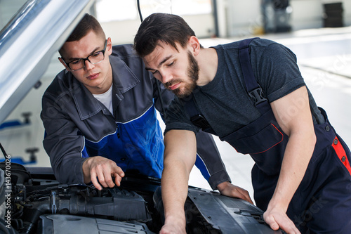 Two mechanics working on a car