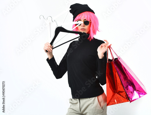 fashionable sexy girl in pink wig holding package with hangers