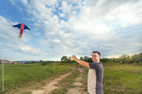 Portrait of smiling young man flying a kite on a windy summer day