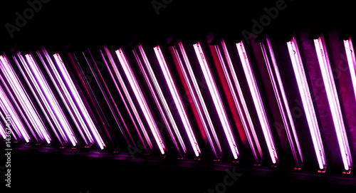 long lamp divided into sections with lights and gradient effect against dark office ceiling photo