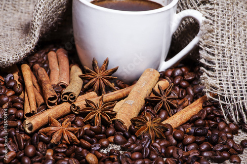 Coffee beans and cinnamon on a background of burlap. Roasted coffee beans background close up. Coffee beans pile from top with copy space for text. Seasoning