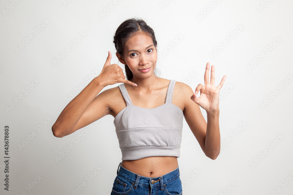 Young Asian woman show with phone gesture and OK sign. Young Asian woman show with phone gesture and OK sign.