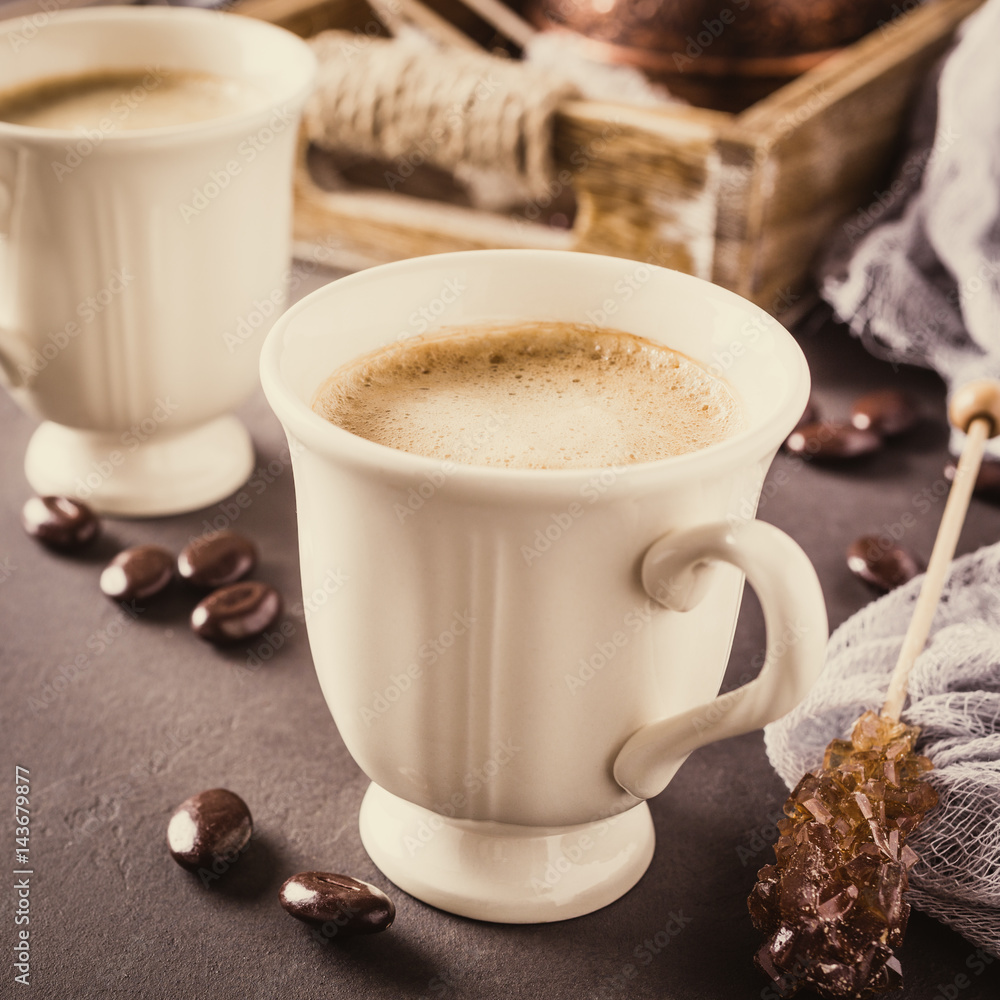 Two retro cups of coffee and old coffee pot on dark brown background. Retro style toned. Two retro cups of coffee and old coffee pot on dark brown background. Retro style toned.