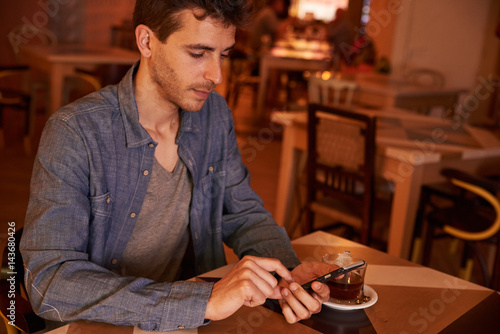 Handsome millenial texting in a restaurant