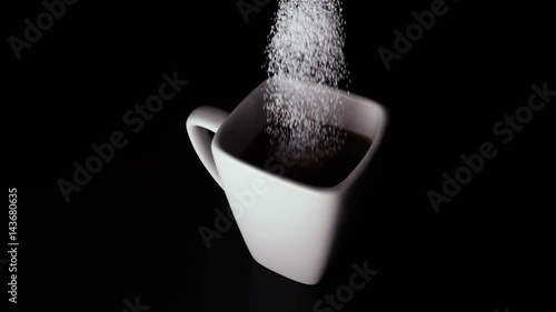 Sweetener from a spoon strews into a cup of coffee on a black background. Slow mo photo