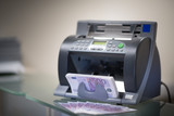 Banknote counter is counting euro banknotes on a blured background