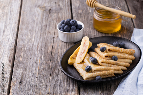 Crepes with honey on wooden background