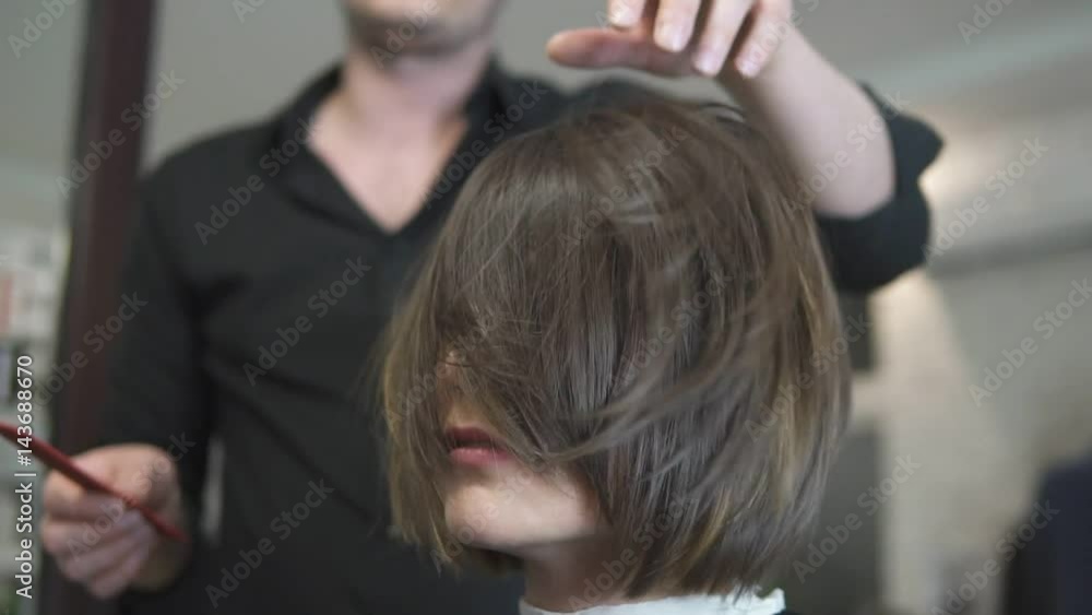 Professional Hair Dresser using brush after haircut. Young woman getting her hair dressed in hair salon. Hair stylist with a hairdryer. Hairdresser at work. Beauty saloon. Shot in slowmotion Professional Hair Dresser using brush after haircut. Young woman getting her hair dressed in hair salon. Hair stylist with a hairdryer. Hairdresser at work. Beauty saloon. Shot in slowmotion