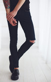 slim legs of young man wearing ripped jeans and leather shoes