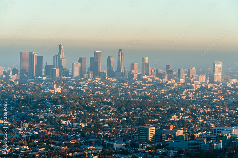 Los Angeles cityscape at evening from Griffith Observatory balcony. View to the skyscrapers in downtown Los Angeles with a straight streets and roads. Smoke in the air in Los Angeles
