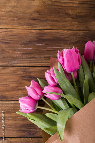 Fototapeta Naklejka Na Ścianę i Meble -  Pink tulips in a package of craft on the wooden background. Pink tulip. Tulips. Flowers. Flower background. Flowers photo concept. Holidays photo concept. Copyspace