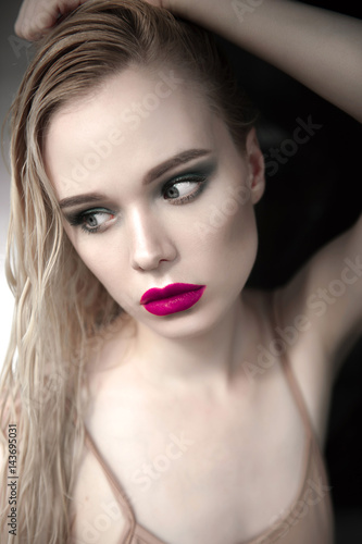 Portrait of beautiful girl model with pink lips and blue eyes with leather belt on her neck, fresh clean highlighted skin. Fashion retouched close up shot. Sad depressed mood