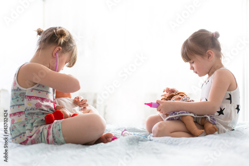 Girls sisters play doctor with dolls, concept maternity