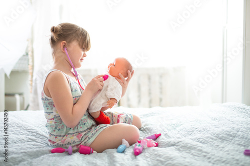 Kid girl playing with doll, playing doctor