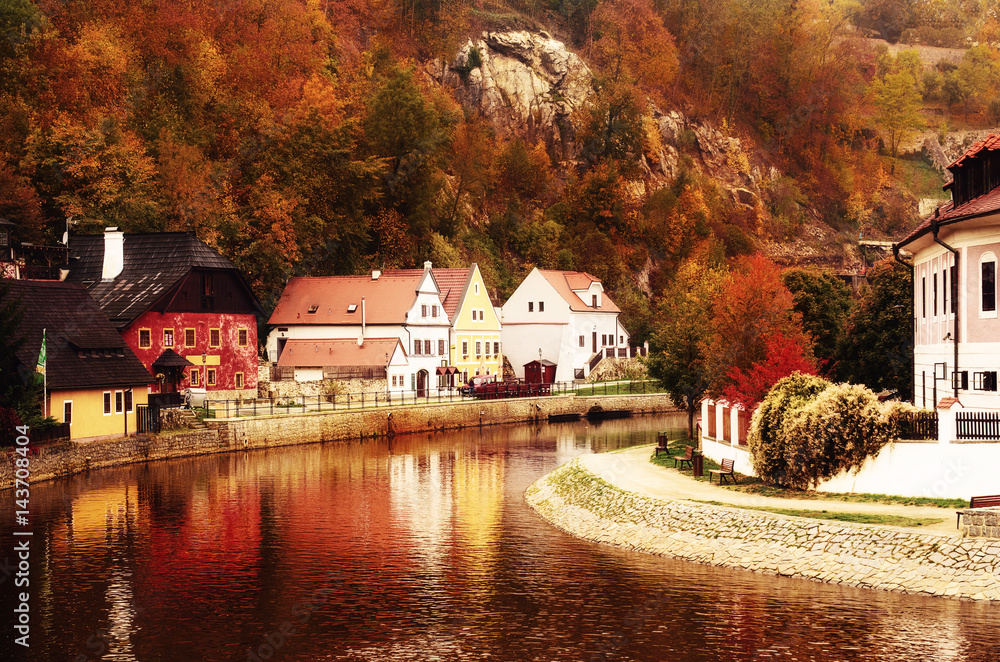 Fototapeta premium Cesky Krumlov - a famous czech historical beautiful town, view to the city river and beautiful autumn street with colorful buildings and fall trees. Travel european background