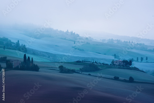 Beautiful summer morning landscape with foggy hills and Tuscany farm houses, travel italian background