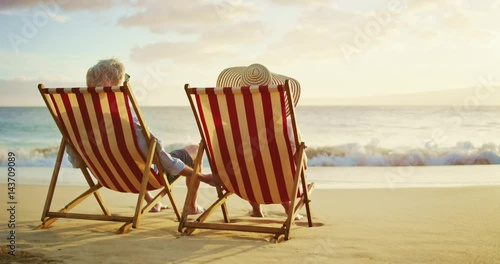 Happy retired couple enjoying beautiful sunset at the beach
