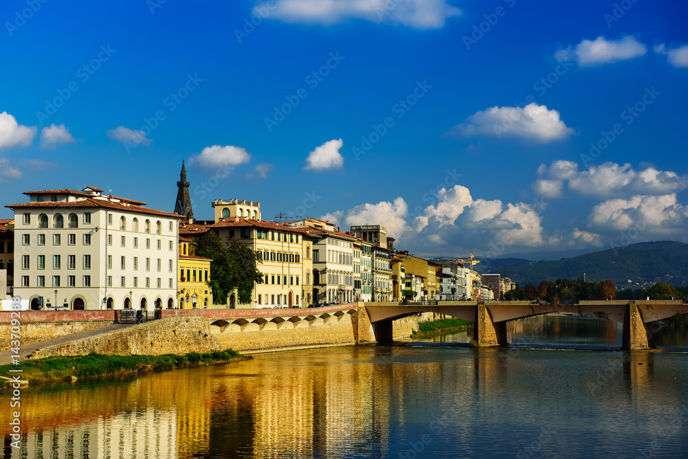 Ponte alle Grazie bridge in Florence, Italy with blue sky, clouds and reflection in the river Arno. Travel outdoor sightseeing background.