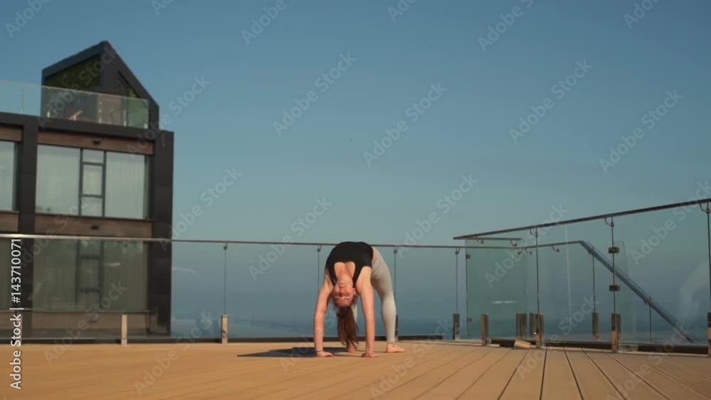 Young attractive female doing yoga on the roof at sea slow motion Young attractive female doing yoga on the roof at sea slow motion