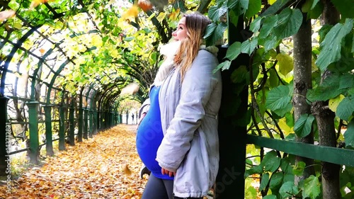 a pregnant woman laughs and rejoices under the fall foliage falling on her face photo