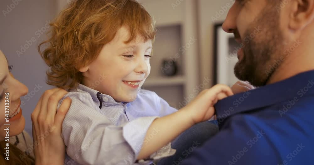 Happy young family spending time together at home. Father holding sun oh his arms. Son hugging parents. Mother, father, son. Happy young family spending time together at home. Father holding sun oh his arms. Son hugging parents. Mother, father, son.